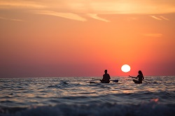 couple canoeing at sunset: tips to vacation mindfully