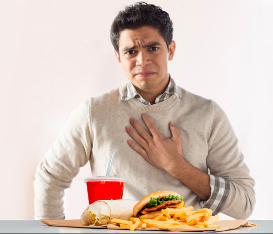 Man with heartburn eating greasy food