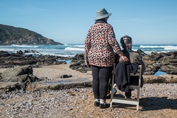Older woman on beach in wheelchair with caregiver