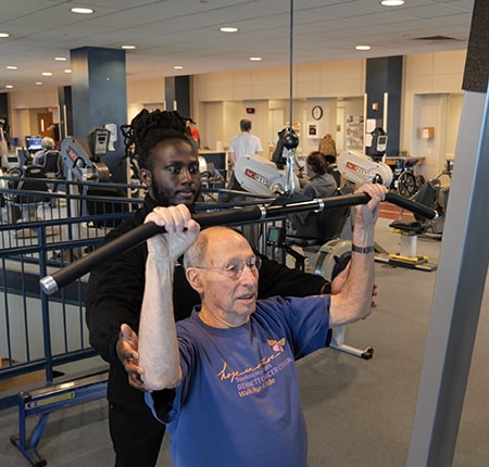 patient lifting weights with a trainer